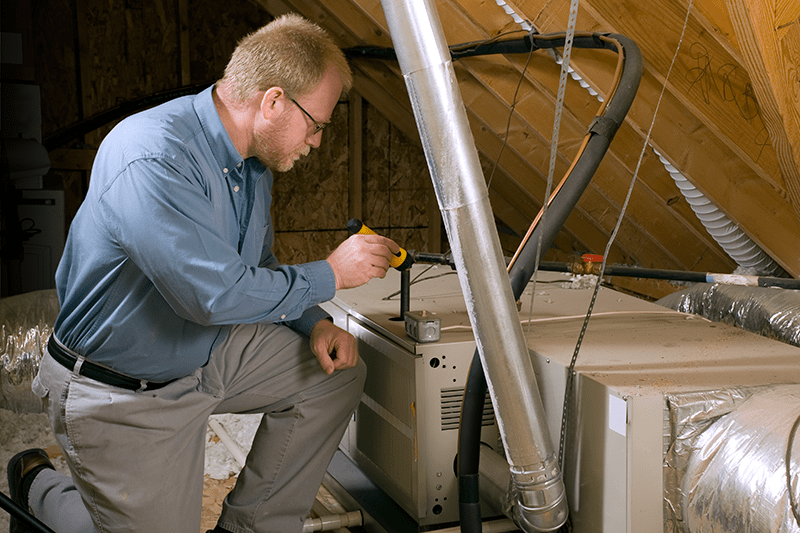 A man works on a furnace. Schedule Your Annual Furnace Inspection Now.