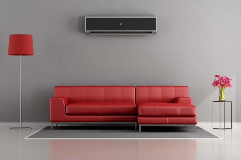 A ductless system, also known as a mini split, can add comfort to areas of your Virginia home where ductwork cannot reach. Whether you are remodeling or adding new living space, our team at Arlington Heating & Cooling is ready to assist. Living room with red sofa and air conditioner - 3d rendering.