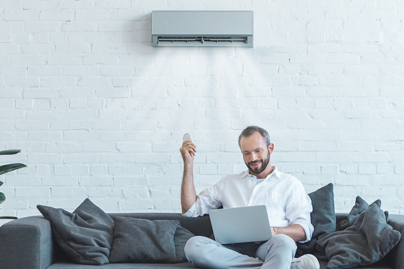 4 Amazing Benefits of Ductless Units. Man turning on a ductless unit.