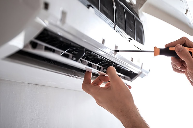 Why Are They Called Ductless Mini Splits? Electrician repairing air conditioner indoors.
